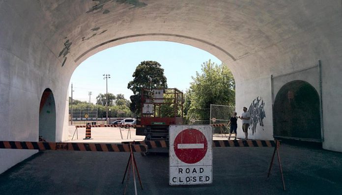 Jill consults with her assistant as they begin the painting process. The road under the archway is closed while the work is underway. (Photo: Bruce Head / kawarthaNOW)