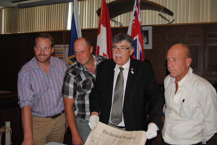 Warden J. Murray Jones displays a copy of The Peterborough Examiner, dated June 9, 1864, that was included in the time capsule. 