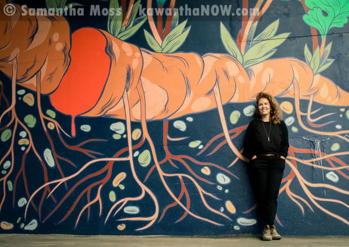 Artist Jill Stanton stands in front of a portion of her mural (photo: Samantha Moss / kawarthaNOW.com)
