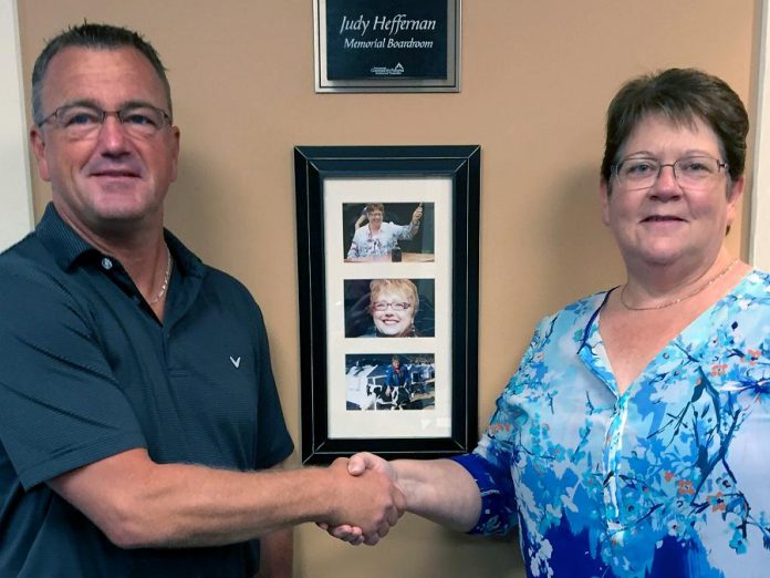 Kim Appleton, chair of the Community Futures Peterborough Board of Directors, welcomes Jeff Day as the organization's new Executive Director. In the background is the memorial boardroom for Judy Heffernan, who served at General Manager for 17 years before passing away suddenly in 2013.