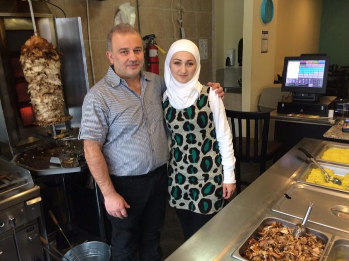 Syrian refugees Mohammad and Randa Alftih pose with some of the authentic Mediterranean food served at their new restaurant, OMG, in downtown Peterborough. (Photo: Eva Fisher / kawarthaNOW)