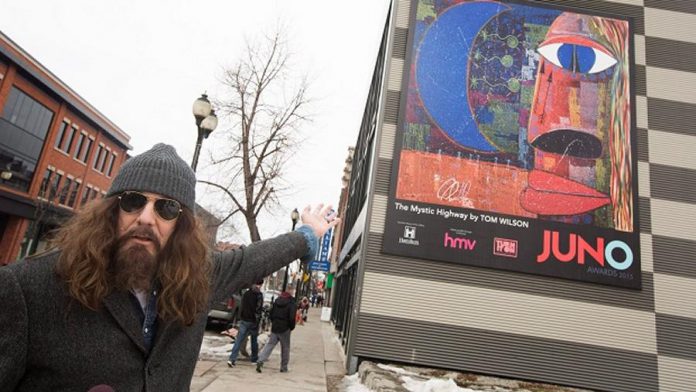 When he stopped drinking in 1997, Tom Wilson began painting in his unique Picasso-like style, which includes intricate inscribing of song lyrics and stories onto the canvas. Here he's pictured in front of "The Mystic Highway", a mural commissioned by the Canadian Academy of Recording Arts and Sciences and the City of Hamilton for the 2015 Juno Awards. (Photo: The Canadian Press / Peter Power)