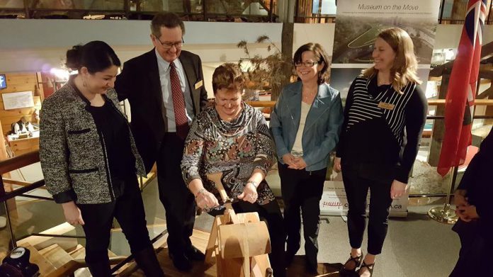 Chief Phyllis Williams of Curve Lake First Nation carves a paddle as MP Maryam Monsef, museum board chair Bill Morris, Peterborough city councillor Lesley Parnell, and musueum general manager Carolyn Hyslop look on  (photo: Jeannine Taylor / kawarthaNOW)