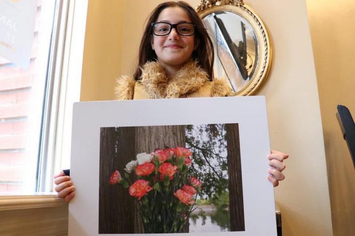 Zienah with one of her photographs that will be display at the Newcomer Children's Photography Project exhibit (photo courtesy of New Canadians Centre)