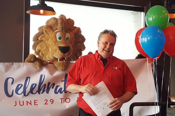 Terry Gueil, Executive Director of Peterborough DBIA, announces the line-up of Canada 150 festivities in downtown Peterborough, with mascot King George in the background (photo: Jeannine Taylor / kawarthaNOW)