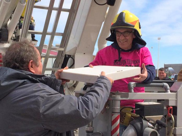 Using its aerial ladder, the Peterborough Fire Department will deposit Paul "Relly" Rellinger on the roof of The Brick. Here he is at last year's event, accepting a pizza donated by Peter Bouzinelos of The Pizza Factory. (Photo: Habitat for Humanity)