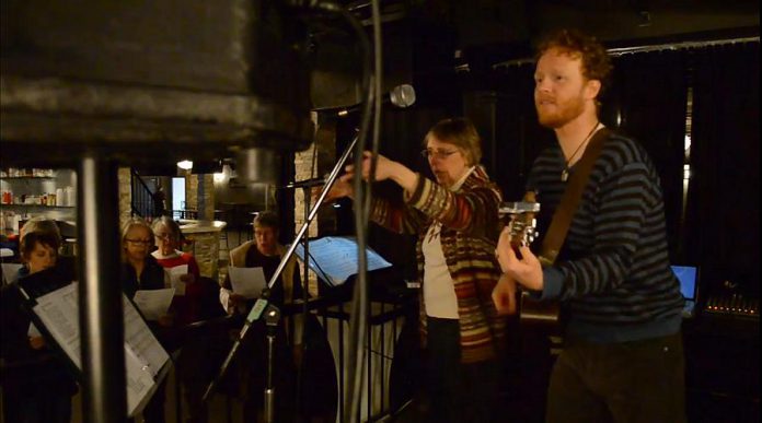 Choir leader Linda Clark conducts the 3 Alarm Choir while musician Luke Lee Burton accompanies on guitar.