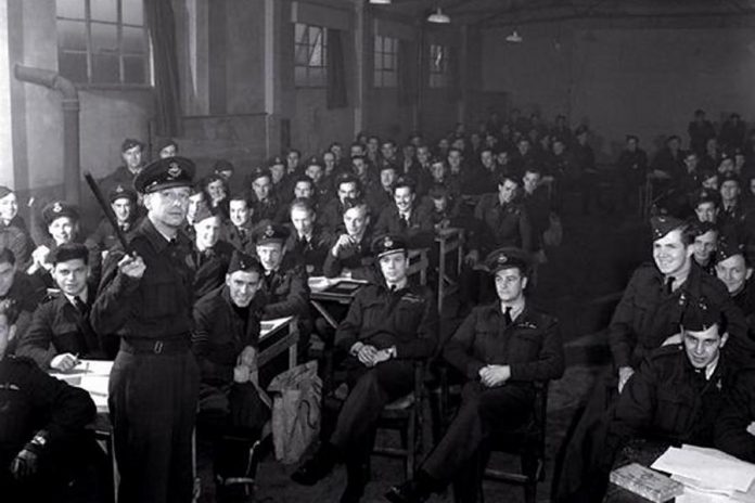 Crew members of No. 428 and No. 434 Squadrons RCAF being briefed before a night mission to Essen, Germany in October 1944. (Photo:  Department of National Defence PL-33941)