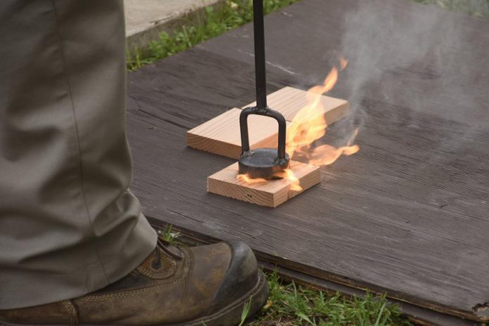 Branding a reclaimed gate log with the Parks Canada logo. (Photo: Parks Canada)