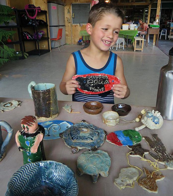 A camper poses with an art project he created at camp. Every day, campers will spend some or all of the day creating with clay, guided step-by-step by qualified instructors through the process. (Photo:  Kawartha Potters' Guild)