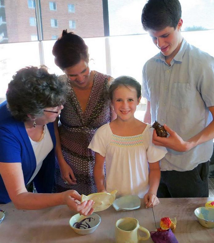 A camper shows off her work to her family. On Fridays, friends and relatives are invited to the Guild to view the artwork on display made by the kids. (Photo:  Kawartha Potters' Guild)