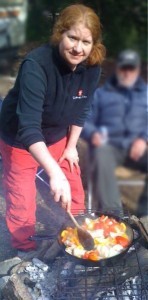 Elaine McCarthy cooking over an open camp fire.