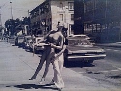 Sally playing the part of a most cooperative ingénue as her and her counterpart stroll past the old Examiner building.