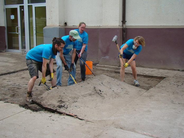 Volunteers lift chunks of asphalt in front of the Brock Mission to expose the soil underneath. The space will be transformed into a garden, which will allow rainwater to soak into the ground, diverting it from nearby storm drains.