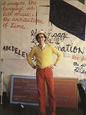 Dennis Tourbin posing in front of a collage of his work, which often dealt with how we receive and understand language (photo courtesy of Public Energy)