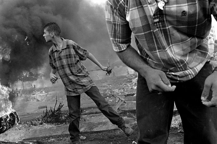 Since the 1980s, photojournalist Larry Towell has travelled to areas of conflict, documenting both violence and people's everyday lives. A major theme in his work is landlessness. This photo shows Palestinian boys throwing stones at Israeli soldiers in Ramallah, West Bank, in October 2000 (photo: Larry Towell)