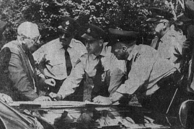 In this 1961 photo from the Peterborough Examiner, Inspector J.A. Stringer (left) explains search strategy to OPP officers after the robbers abandoned their vehicles. This and other photos appear in Grace Barker's 2006 book The Bad Luck Bank Robbers, which documents the case.