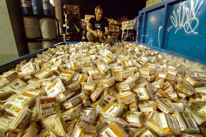 Grant Baldwin, producer of the film "Just Eat It" that focuses on the topic of food waste, kneels over a dumpster of discarded hummus. Food waste in Canada is valued at a staggering $31 billion in 2014, up 15% from 2013.