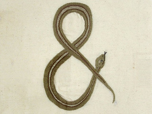 A number of artistic creations like collage, painting, and needle-work, like this ampersand snake, feature among the throng of found artifacts (photo courtesy of Paulo Fortin at Evans Contemporary)