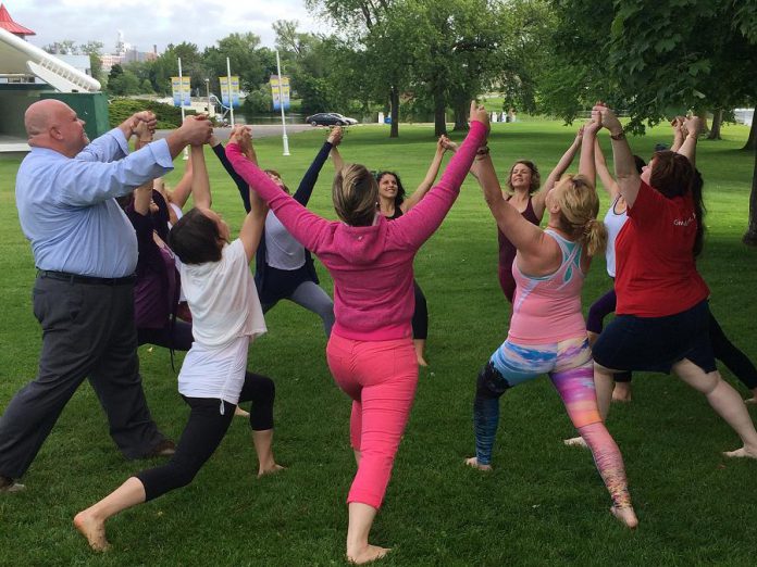 Jim Russell, CEO United Way Peterborough & District, joins in a group pose at Del Crary Park during the June 16th media launch for the Peterborough Yoga Festival, which takes place at the park on Sunday, June 21st