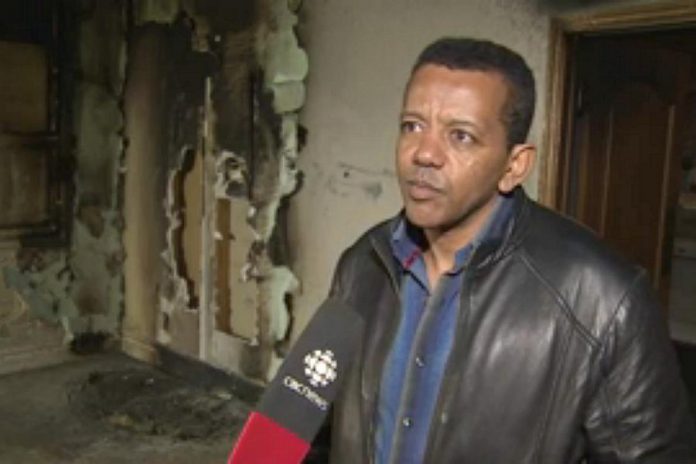 Kenzu Abdella, president of the Kawartha Muslim Religious Association, being interviewed by CBC Television as he surveys the fire and smoke damage to the mosque (photo: CBC Television)