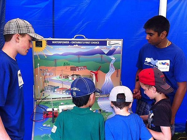 High school student volunteers lead children through an interactive activity centre that demonstrates how water is used to create electricity