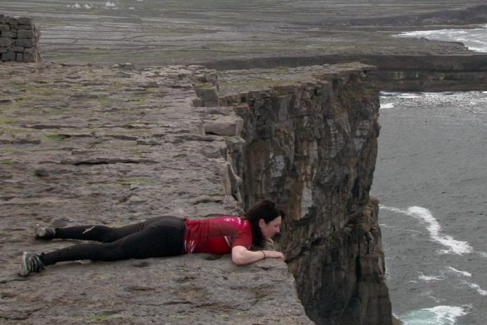 Megan Murphy lying at the edge of a cliff on the Aran Island in Ireland in a scene from her documentary film Murphy's Law, which chronicles her journey to retrace her deceased father's bicycle trip across Ireland (photo courtesy of Megan Murphy)
