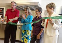 MPP Jeff Leal cuts the ribbon at Myrtle's Kitchen at the downtown location of the newly rebranded Peterborough Public Health, as Medical Officer of Health Dr. Rosana Salvaterra, Jillian Bishop of The Nourish Project, and Leslie Orpana of the Ontario Trillum Foundation look on (photo: Paul Rellinger / kawarthaNOW)