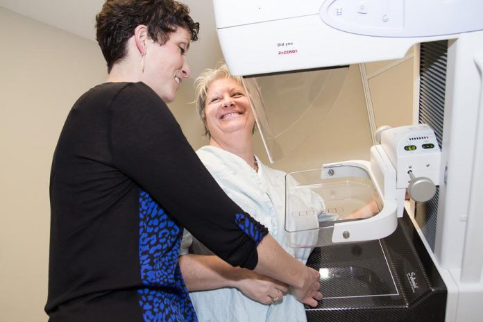 Jill Cummings, Senior Mammography Technologist at PRHC's Breast Assessment Centre, demonstrates how a mammography machine works to writer Jeanne Pengelly. PRHC Foundation is seeking community donations to purchase three new state-of-the-art mammography machines for the centre, one over each of the next three years. (Photo: Linda McIlwain / kawarthaNOW)