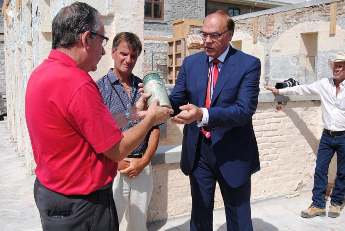 MPP Jeff Leal and Mayor Daryl Bennett handle the time capsule, a sealed glass jar buried in 1864 at the site of the old Peterborough County Jail.