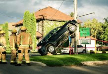 Firefighters look at the scene of an accident in East City, Peterborough, where a car climbed up a hydro pole. The car is being held in place with various supports until it can be safely lowered to the ground. (Photo: Samantha Moss)