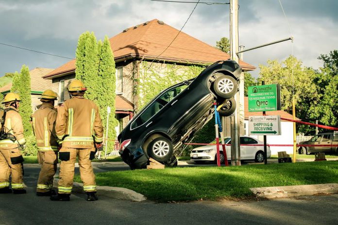 Firefighters look at the scene of an accident in East City, Peterborough, where a car climbed up a hydro pole. The car is being held in place with various supports until it can be safely lowered to the ground. (Photo: Samantha Moss)