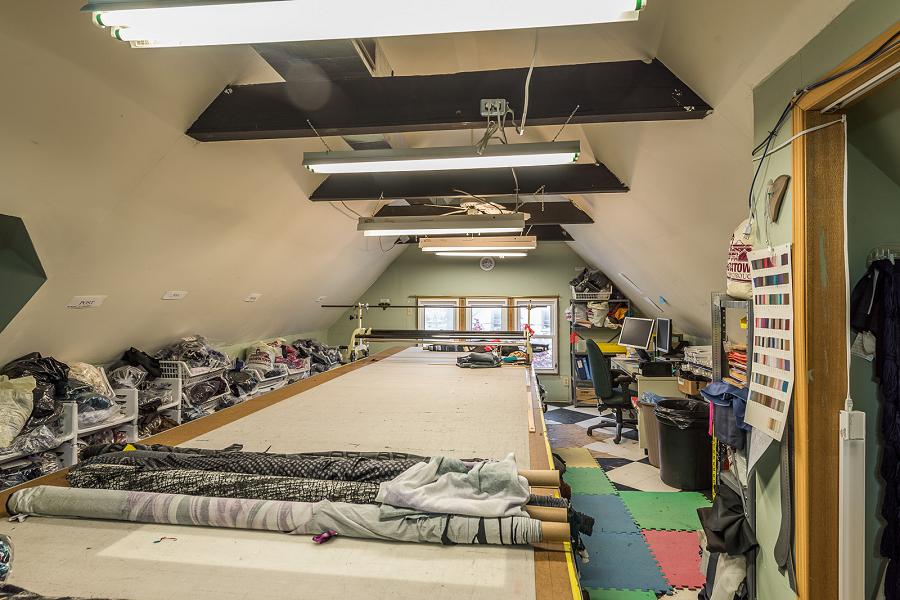 The spacious attic features exposed trusses, and is currently used for fabric storage. (Photo: Doug Logan, Fine Homes Photography)