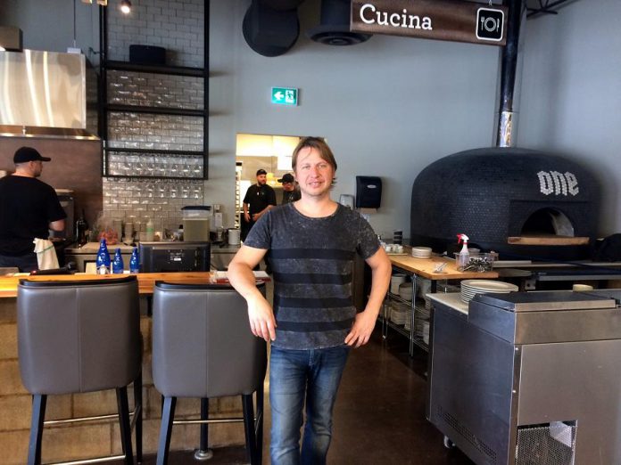 Co-owner and Manager Matt Choma stands in front of the wood-fired pizza oven in the restaurant section of One Fine Food, a new Italian-inspired restaurant and marketplace opening this week in Peterborough. (Photo: Eva Fisher / kawarthaNOW)