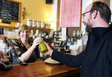 Maggie Lightfoot passes a bottle of tap water over the counter to GreenUP Water Programs Coordinator Dylan Radcliffe at Black Honey Coffee House on Hunter Street, Peterborough. Black Honey is one of many businesses that have signed up as part of BlueWPtbo.ca, an online app mapping businesses in the city where anyone can fill up their reusable water bottle for free. (Photo courtesy of GreenUP)