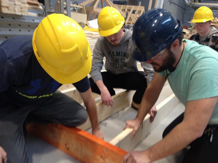 Fleming College Carpentry Techniques students Daniel Widdis, Carter Clark, and Benjamin Wright working on a wall frame destined for the new Peterborough County Agricultural Heritage Building at Lang Pioneer Village in Keene (photo: Paul Rellinger / kawarthaNOW)
