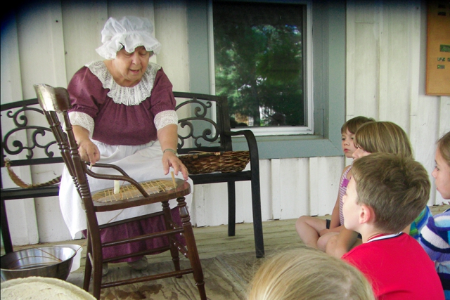 Children learn hands-on activities considered 'everyday' over a hundred years ago, like chair caning taught by volunteer Louise Plante. (Photo: Kawartha Settlers' Village)