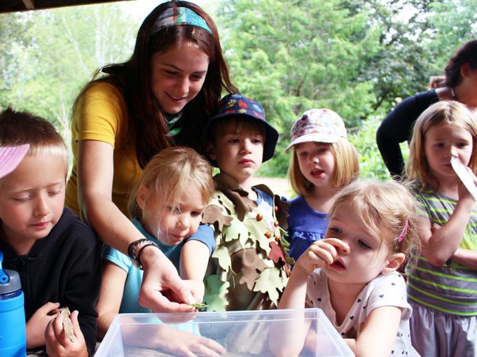 A GreenUP Environmental Educator shows a caterpillar to campers at GreenUP Ecology Park's Earth Adventures day camp. The campers found several monarch caterpillars that they are observing over their week at camp to watch as they grow each day, change into a chrysalis, and emerge as adult butterflies. (Photo: Karen Halley)