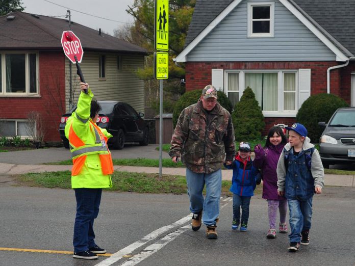 A group walks safely at a school crossing with the help of a City of Peterborough crossing guard. Walking to school is a great way for kids to have a little fun and make connections with neighbours and friends. The Crossing Guards of Peterborough would like to remind drivers to slow down when approaching a school-crossing zone to ensure everyone’s safety. (Photo: GreenUP)