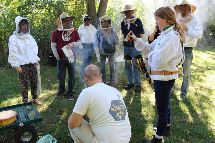 GreenUP's Resident Beekeeper Marcy Adzich shows a group of community members how a hive smoker works at an Open Hive! event at GreenUP Ecology Park in Peterborough while a member of the GreenUP Community Beekeeping Program assists with the demonstration. The hive is smoked so that the bees will not sting when the group enters the hive. (Photo: Karen Halley)