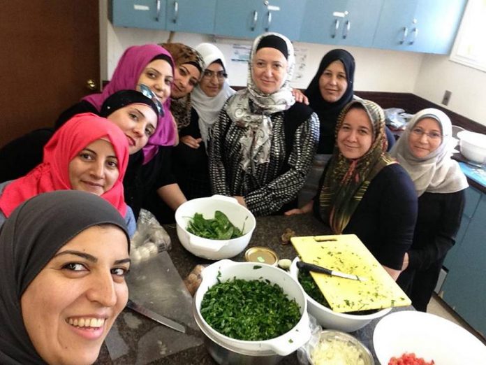 Reem, Fatma, Wesal, Hayfa, Ramya, Enas, Jommana, Dilshah, Ameena and Rafa make Syrian dishes through Newcomer Kitchen, a program led by the New Canadians Centre and hosted in the kitchen of the Beth Israel Synagogue. (Photo: Newcomer Kitchen)