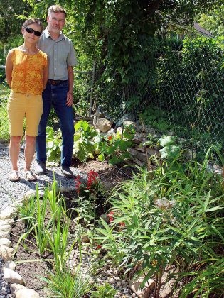 Peterborough residents David Marshall and Barbara Moffat next to a rain garden they installed in their back yard after being inspired by a GreenUP Ready For Rain Workshop. They have transformed their entire property by installing many water-wise features including rain barrels, a smart irrigation system, and by de-lawning the entire property to replace grass with native plants and wildflowers. (Photo courtesy of GreenUP)