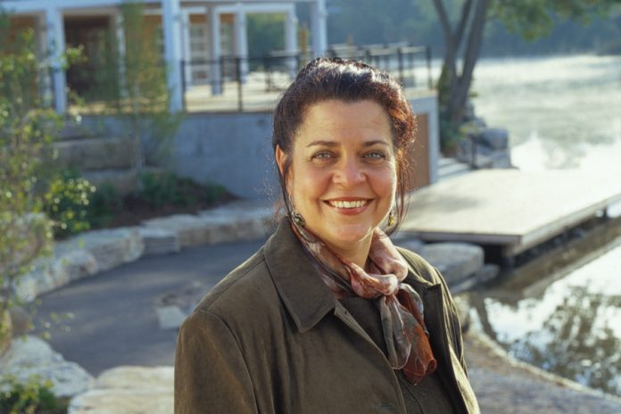 Jeannine Taylor, owner and publisher of online publisher kawarthaNOW.com, has been recognized for her community involvement, including a civic award for chairing a fundraising committee for the development of Millennium Park, pictured in the background. (Photo: Michael Cullen)