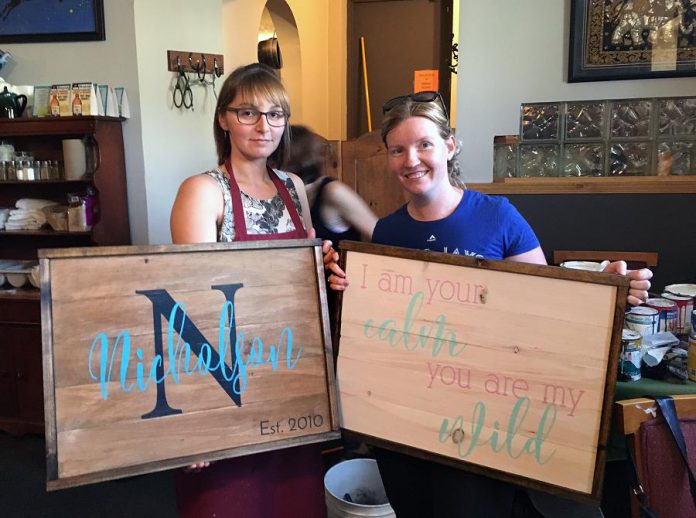 Suelynn Howden, left, and Kate Griffin with their final masterpieces from a workshop at the Black Horse Pub. Howden created a sign brandishing her surname for her home's front entrance and Griffin's sign displays a line from the book, You Are My I Love You, for her children's bedroom. (Photo: Anchor & Co.)