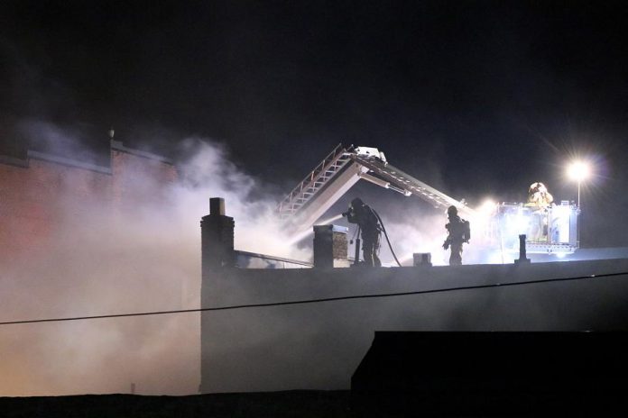  Firefighters battle the fire from the roof adjacent to the burning building.  (Photo: Sean Bruce)