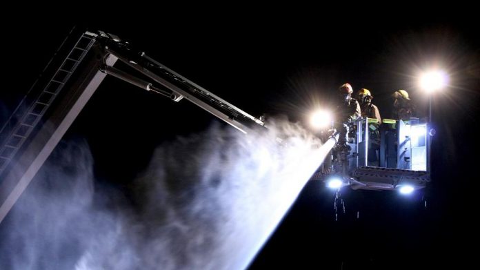 A fire crew directs water on the roof of the burning building.  (Photo: Sean Bruce)