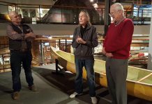 Gordon Lightfoot speaks at The Canadian Canoe Museum as museum curator Jeremy Ward (left) and Lightfoot's friend and fellow canoest Fred Gaskin looks on. The yellow canoe behind Lightfoot is one of three canoes he is donating to The Canadian Canoe Museum collection, along with one canoe donated by Gaskin. (Photo: Jeannine Taylor / kawarthaNOW.com)
