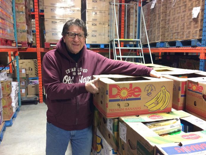 Dave Ralph, Chair of the Kawartha Food Share, stacks boxes of sorted food for families throughout the Kawarthas. (Photo: Eva Fisher / kawarthaNOW.com)