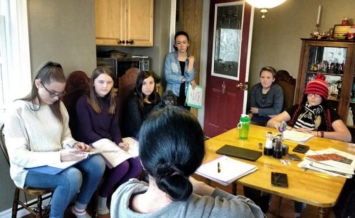 Planet 12 Productions director, writer, and co-founder Derek Weatherdon (with his back to the camera) during a kitchen meeting with the company's six talented young performers: Aimee Gordon, Emma Meinhardt, Emily Keller, Abbie Dale, Isaac Maker, and Samuelle Weatherdon. The company is staging a new version of "The Reluctant Dragon" for local schools and will be taking "Boy Wonders" to the Toronto Fringe Festival in 2018. (Photo: Sam Tweedle / kawarthaNOW.com)