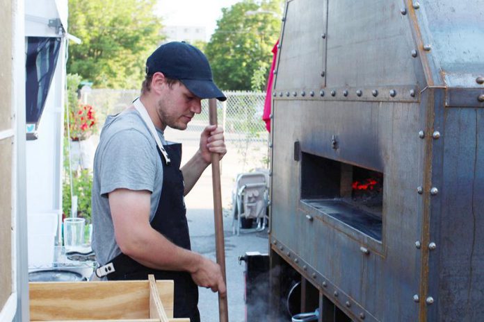 Hard Winter Bread Company co-owner Graham Thoem with the bakery's custom-made wood-fired bagel oven, which is mobile so they can take it to local farmers' markets and bake fresh bagels on site.  (Photo courtesy Hard Winter Bread Company)